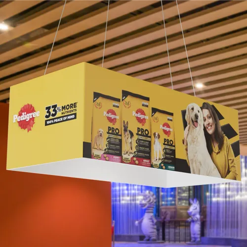 A hanging rectangular trade show display features the Pedigree brand, dog food products, a woman smiling with a dog, and text '3% MORE' and '100% PEACE OF MIND.'